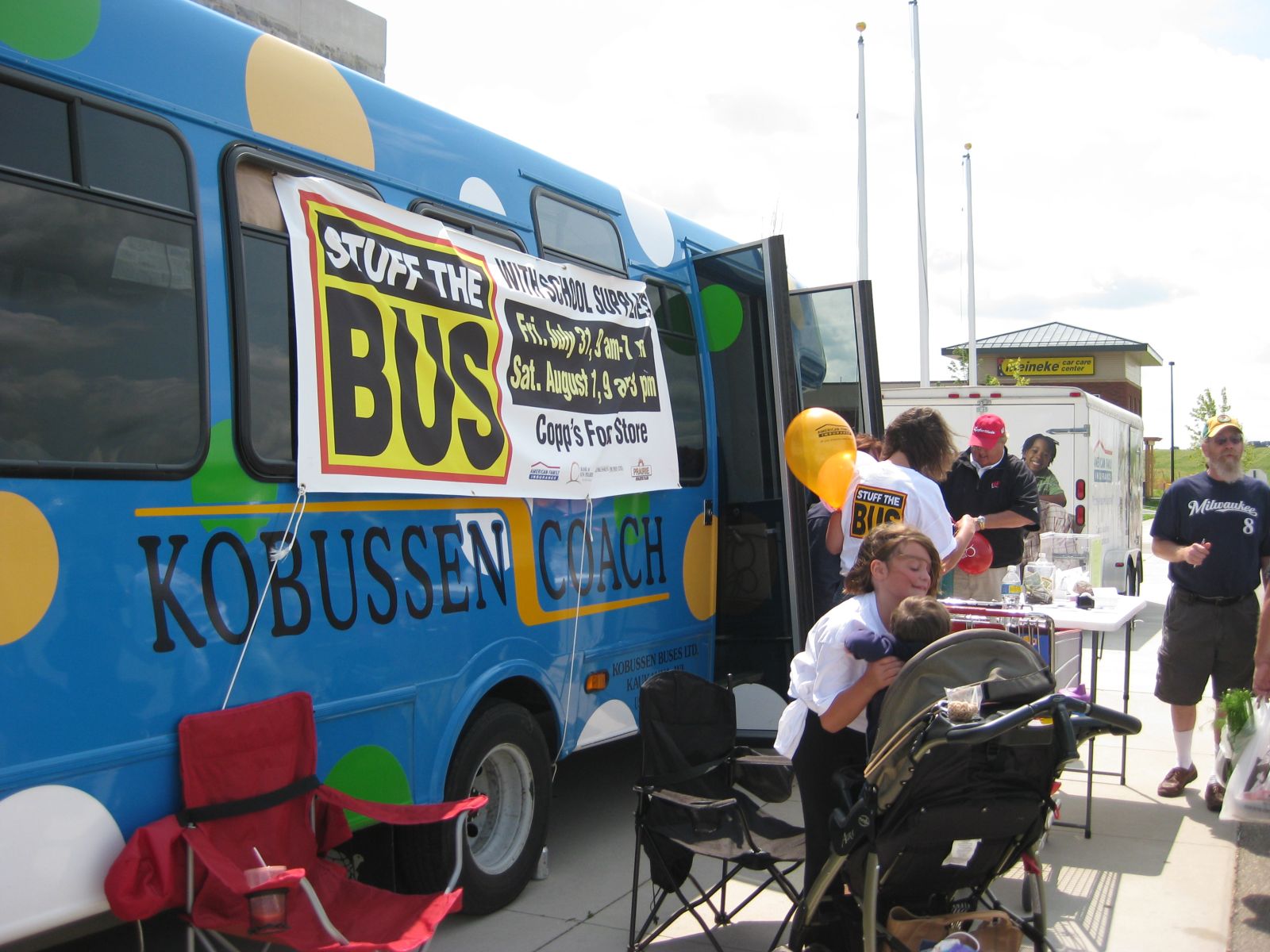 A large blue bus with a Stuff the Bus Banner on the side is surrounded by kids and adults.